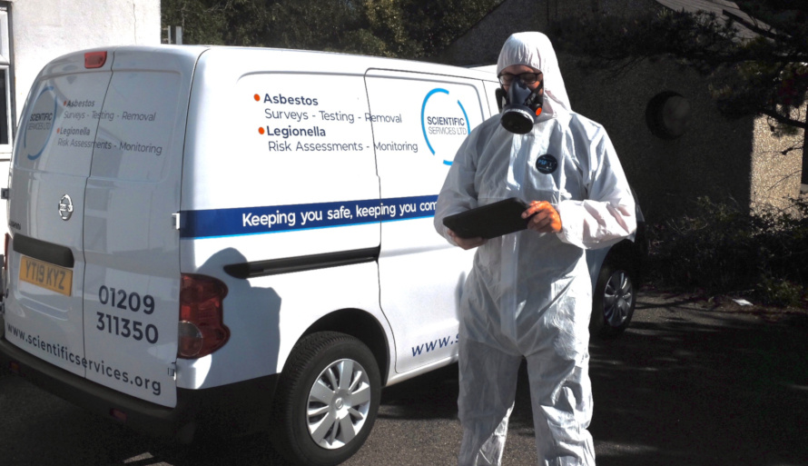 Asbestos surveyor looking at a tablet by a mobile laboratory