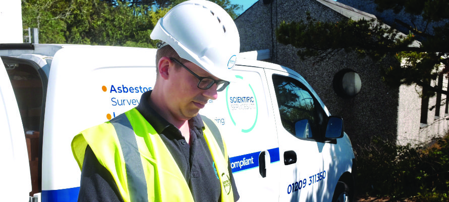 Asbestos surveyor and mobile laboratory Asbestos surveyor looking at a tablet by a van.