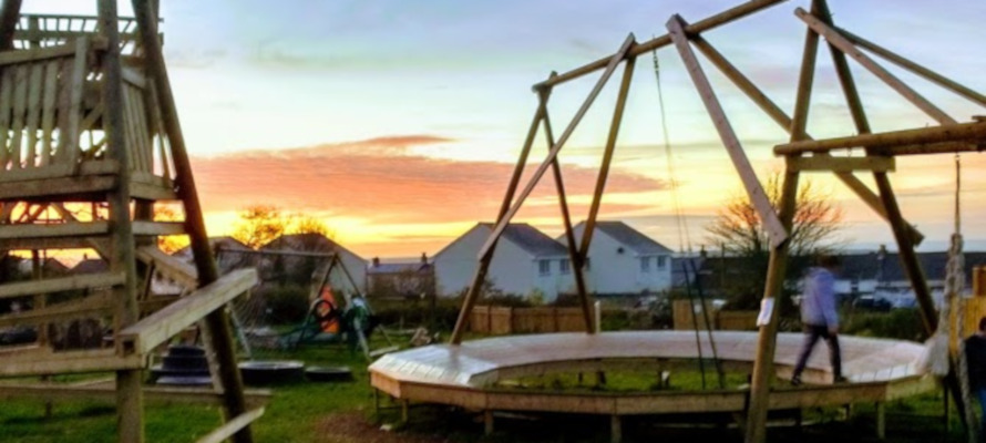 Children playing at Gwealan Tops Adventure Playground with a sunset.