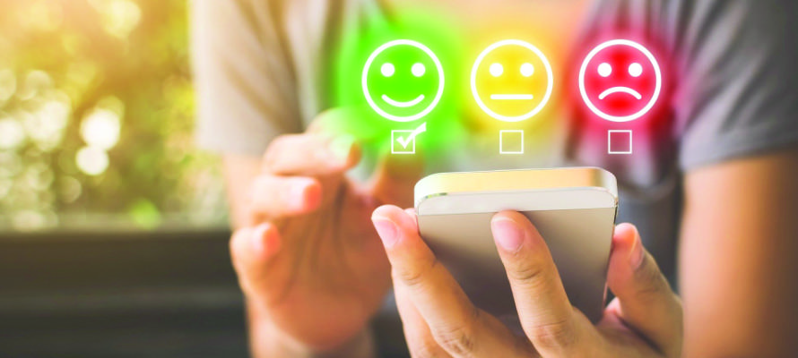 Satisfaction Survey Image Person completing a survey on a mobile phone with rating symbols.