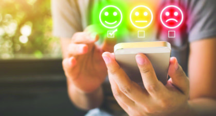 Person completing a survey on a phone with rating symbols.