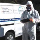 Asbestos consultant looking at a tablet with a van